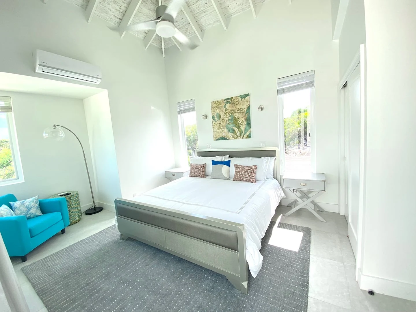 The main bedroom with a king bed, reading chair and high timber ceiling